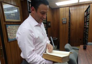 In his and his father's law office, Mike Testa admires a book published in 1919 from the library built by his grandfather, the Honorable late Frank J. Testa.