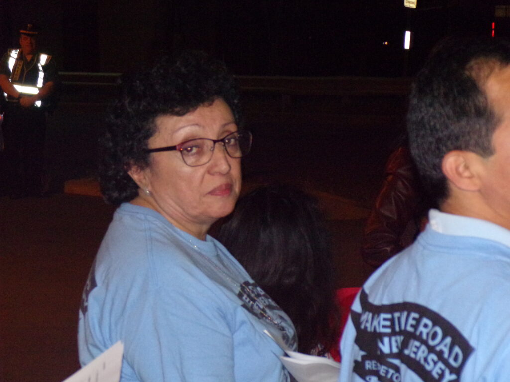 Janet waits to address the crowd in Kearny outside the warehouse where her brother died.